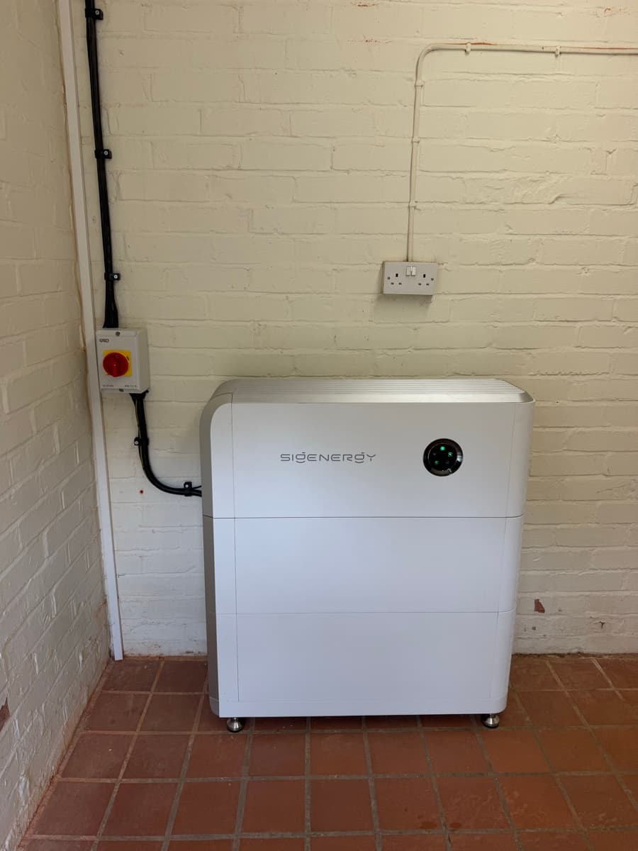 A Sigenergy SigenStor battery standing in a garage against a painted brick wall.